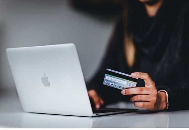 Como funciona um cartão de crédito Pessoa com notebook e cartão de crédito na mão